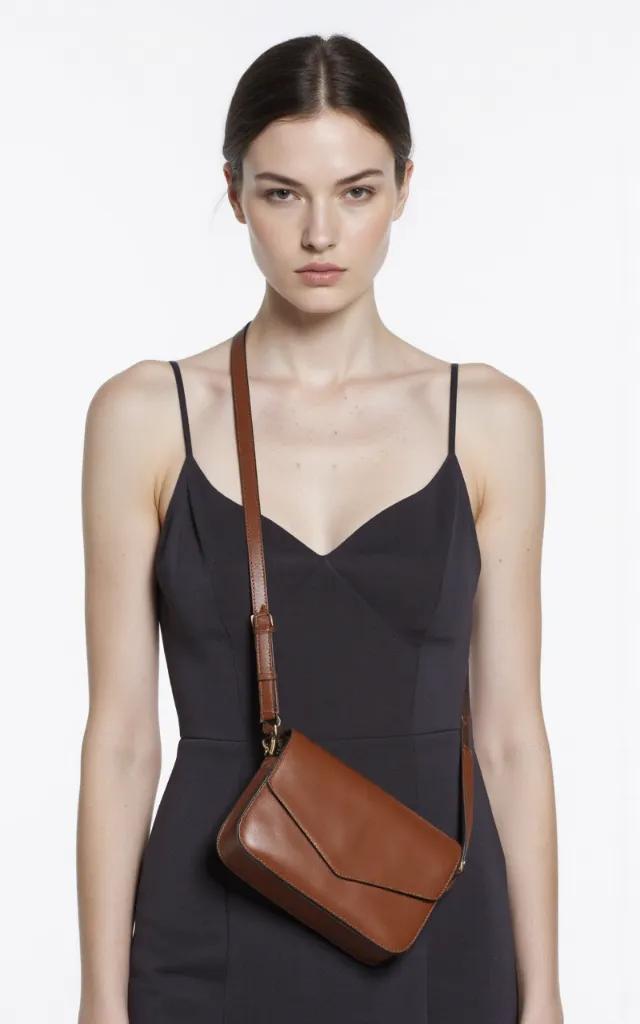 A French female model with a Cross   body bag, wearing a dress, against a white background, in a front   facing close   up